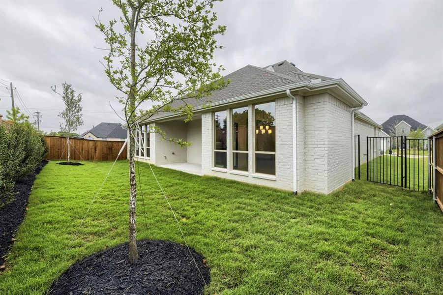 The property features a spacious backyard with a well-maintained lawn, privacy fencing, and a mature tree with dark mulch