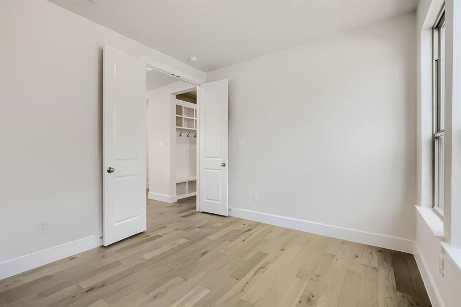 Bright room featuring wood-finish flooring, white walls, and a window with white trim