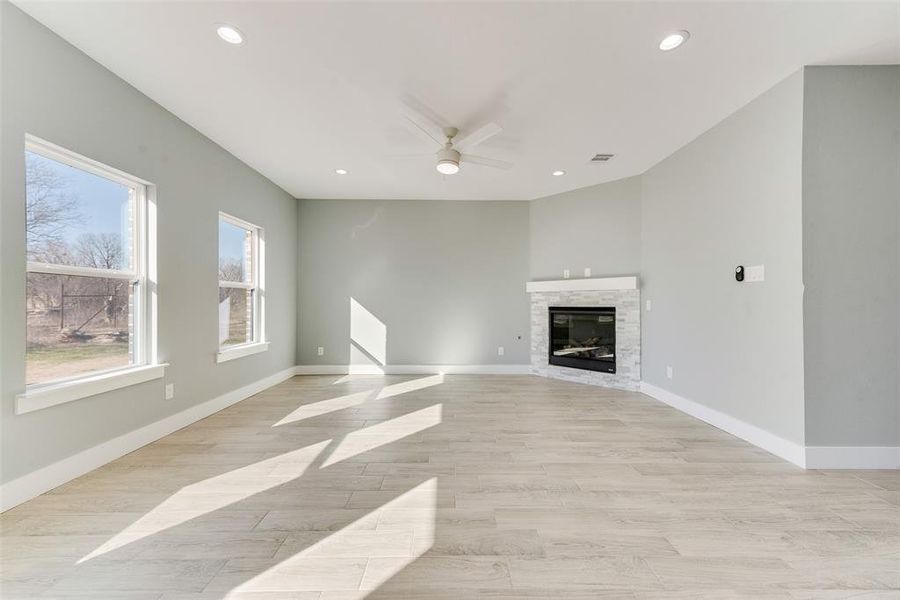 Unfurnished living room featuring a stone fireplace, light hardwood / wood-style floors, and ceiling fan