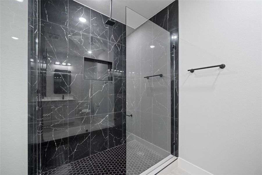 Full bath with a marble finish shower