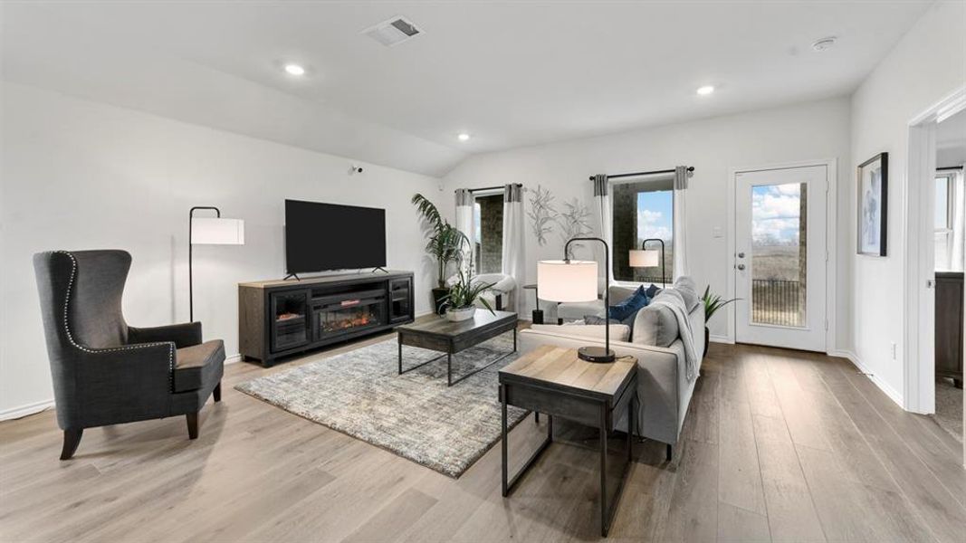 Spacious living area featuring light wood-finish flooring, recessed lighting, and a vaulted ceiling Spacious living area featuring light wood-finish flooring, recessed lighting, and a vaulted ceiling