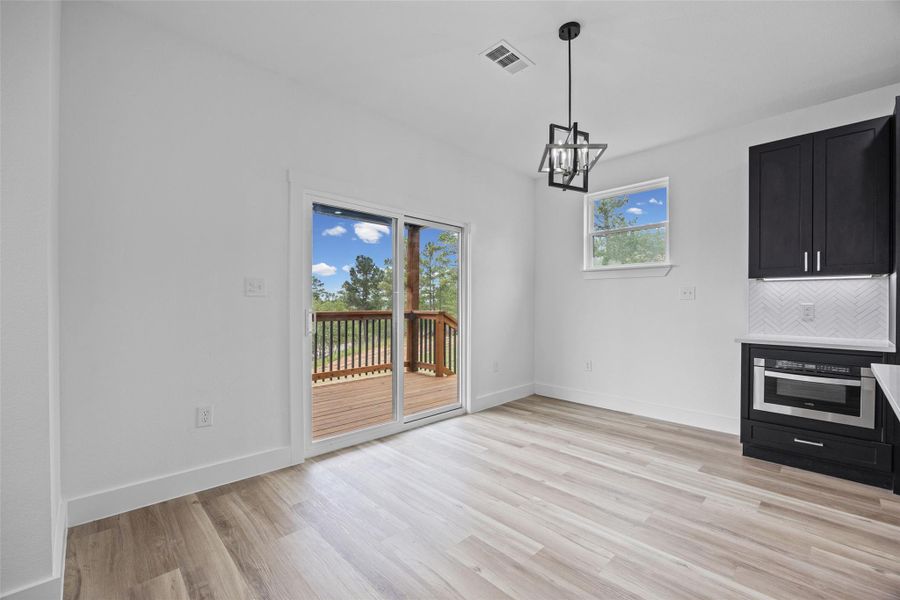Dining area with wood-finish flooring, featuring a modern geometric pendant light Dining area with wood-finish flooring, featuring a modern geometric pendant light