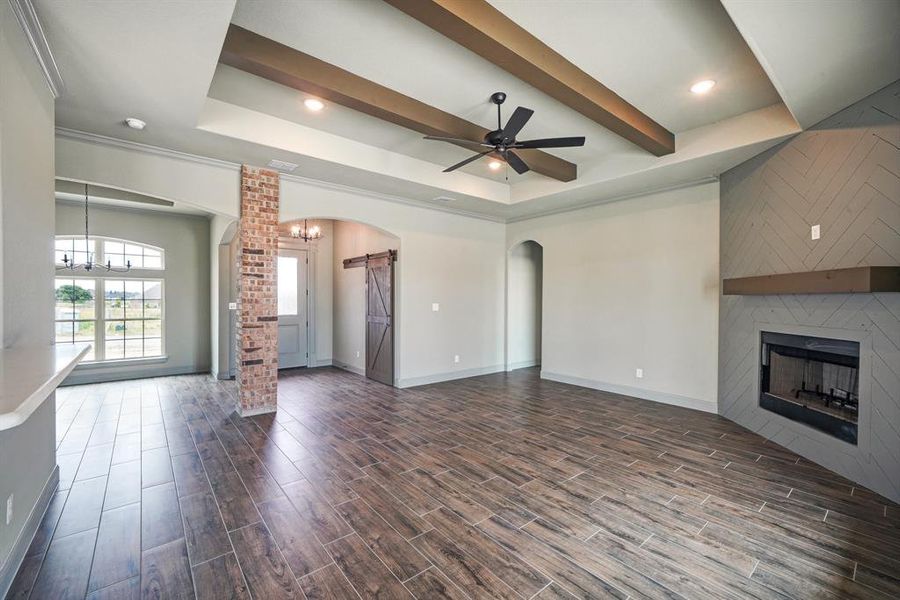 Open floorplan living room with beam ceiling and wood-burning fireplace.