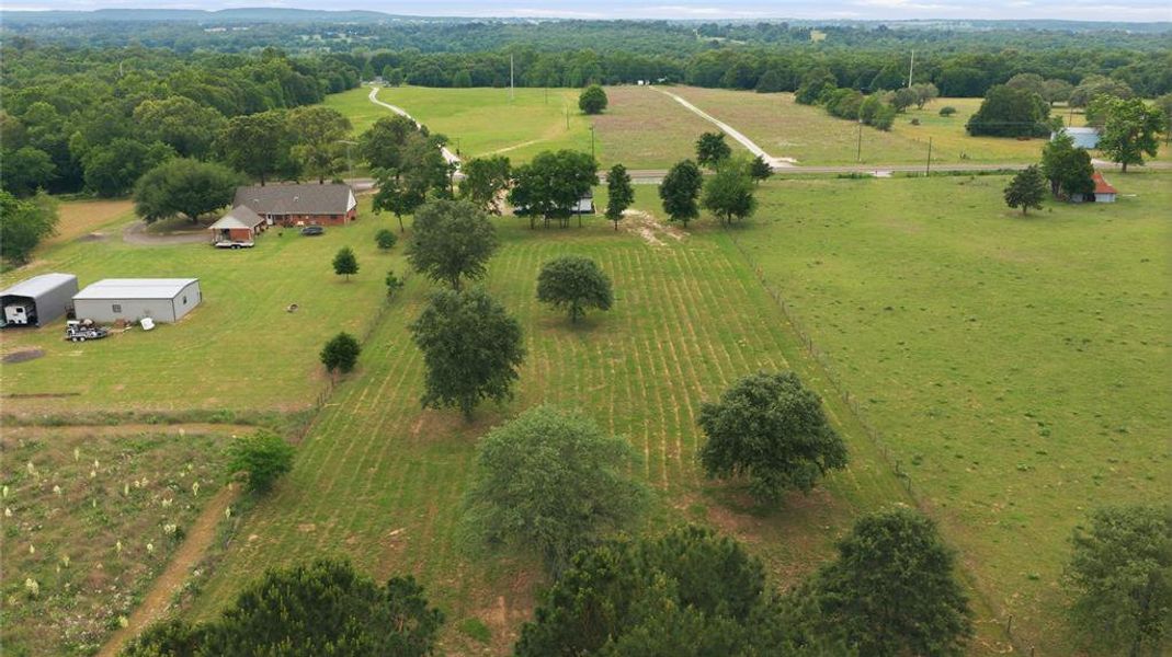 Expansive rural landscape featuring a single-story brick residence with a covered porch