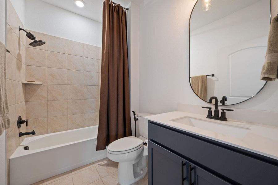 Bathroom with shower / bathtub combination with curtain, vanity, and light tile patterned flooring Bathroom with shower / bathtub combination with curtain, vanity, and light tile patterned flooring