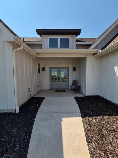 Property entrance with board and batten siding and french doors