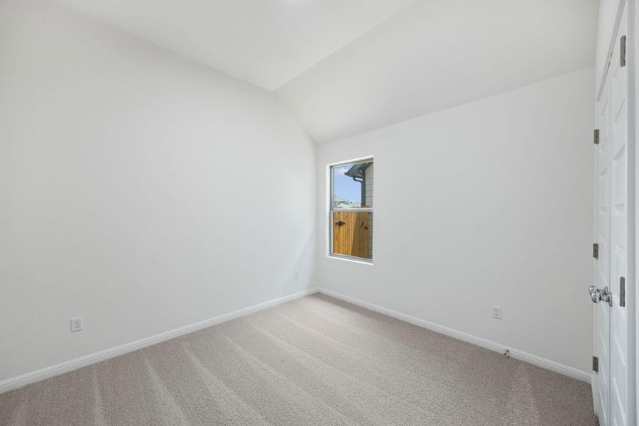 Empty room featuring light colored carpet and vaulted ceiling