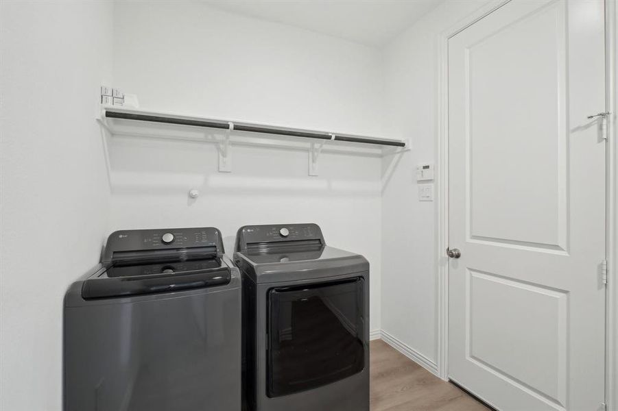 Laundry area with separate washer and dryer and light hardwood / wood-style flooring