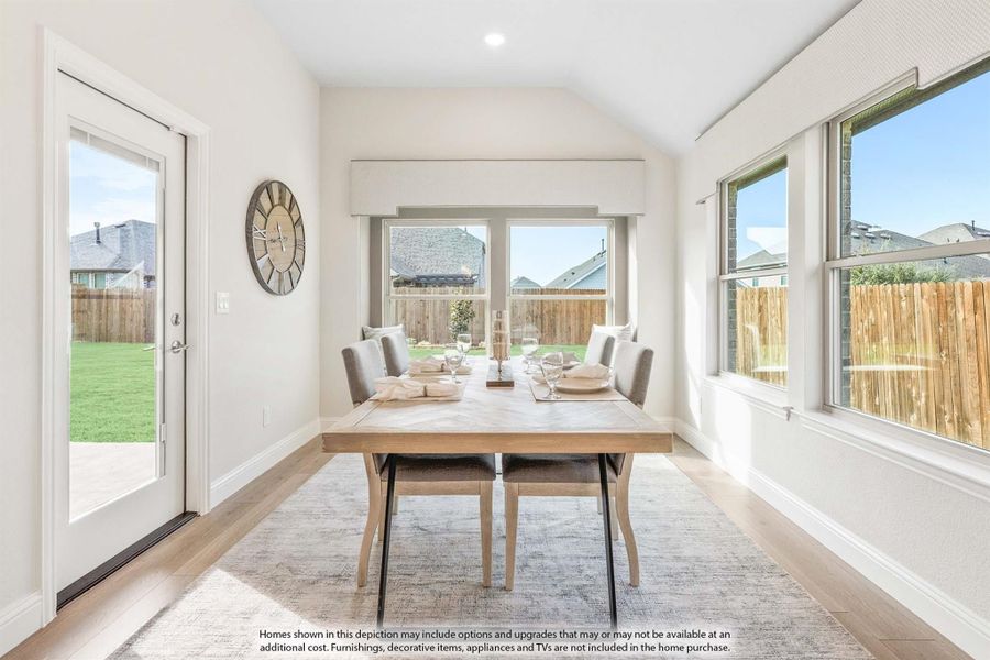 Bright dining room with wood table, gray chairs, vaulted ceiling, and backyard access door