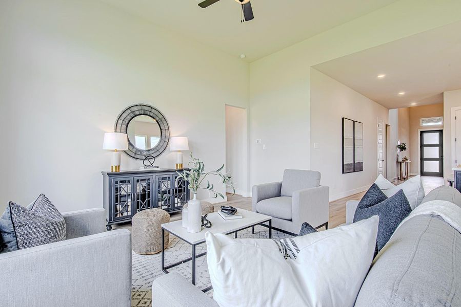 The spacious living area features warm wood flooring, neutral tones, and a view toward the dramatic front entry, adding both elegance and flow.