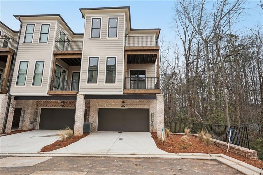 View of front of house featuring concrete driveway, an attached garage, brick siding, and a balcony
