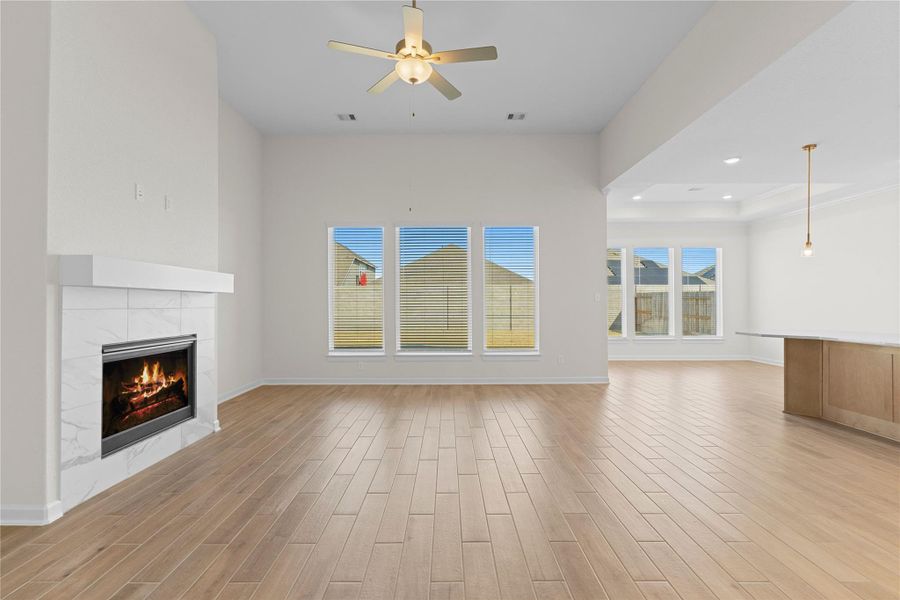 Another angle of the family room showcases the abundance of natural light streaming through large windows, enhancing the airy feel of the space while perfectly complementing the wood like tile flooring, making this room ideal for relaxing or entertaining guests.