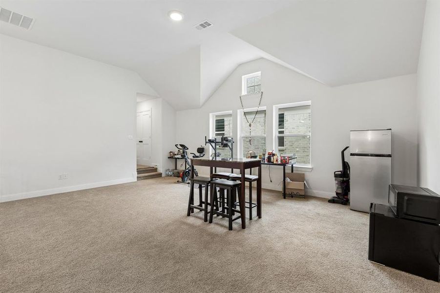 Spacious room featuring vaulted ceilings, light-colored carpeting, multiple windows, and recessed lighting