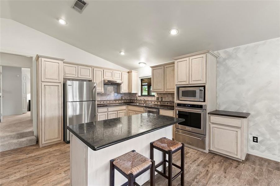 Traditional kitchen featuring stainless steel appliances, built-in oven with warming drawer, electric cooktop, high-end granite countertops, and plenty of storage.