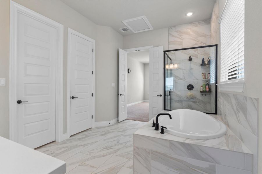 Elegant tile work anchors the soaking tub and glass shower in this primary bathroom.