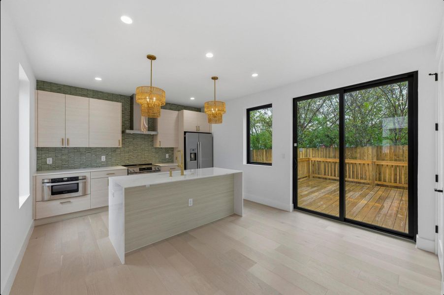 Kitchen featuring pendant lighting, a center island, stainless steel appliances, decorative backsplash, and wall chimney range hood Kitchen featuring pendant lighting, a center island, stainless steel appliances, decorative backsplash, and wall chimney range hood
