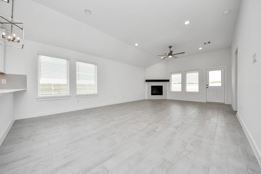 Welcome family and guests to your charming living room! With its high ceilings, recessed lighting, ceiling fan, custom paint, beautiful flooring, and large windows that let in abundant natural light, this room is perfect for gatherings. Sample photo of completed home with similar floor plan. Actual colors and selections may vary.