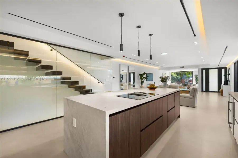 Center island featuring a stone-finish countertop, flat-panel wood cabinetry, and an integrated cooktop Center island featuring a stone-finish countertop, flat-panel wood cabinetry, and an integrated cooktop