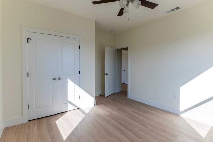 Unfurnished bedroom with light wood-type flooring, a ceiling fan, and a closet