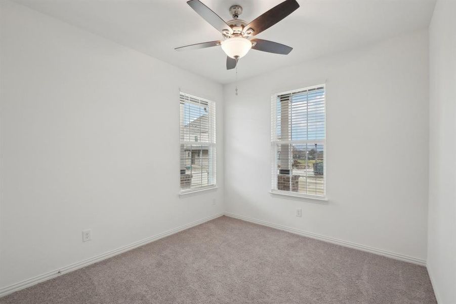 Carpeted empty room featuring ceiling fan