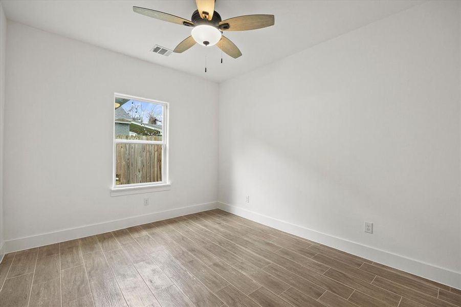 Empty room with wood tiled floors and a ceiling fan