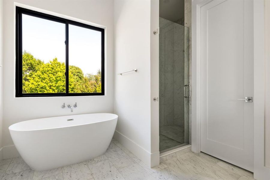 Bathroom featuring a stall shower, a freestanding bath, and light marble finish flooring Bathroom featuring a stall shower, a freestanding bath, and light marble finish flooring