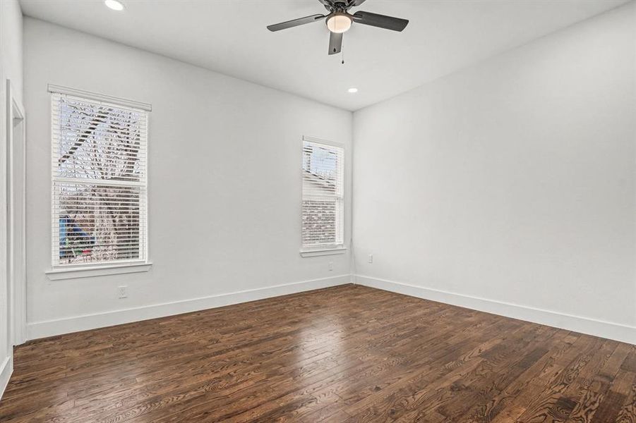 Secondary bedroom with hardwood flooring, lighted ceiling fan, dual windows, double-door closet and recessed lighting.