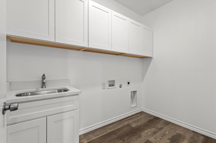 Clothes washing area with hookup for a washing machine, hookup for an electric dryer, sink, cabinets, and dark hardwood / wood-style flooring