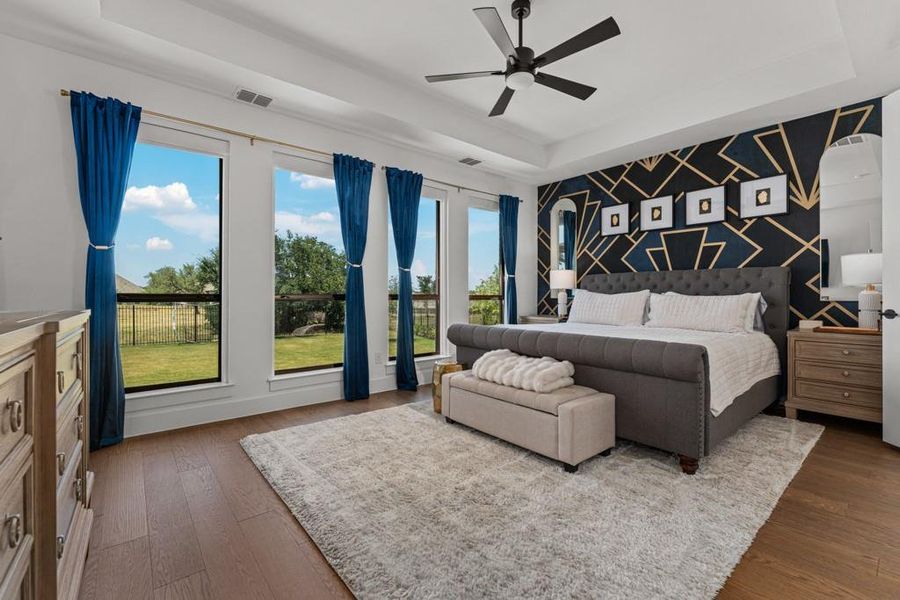 Hardwood floors and generous windows create a naturally illuminated primary bedroom with backyard views. Hardwood floors and generous windows create a naturally illuminated primary bedroom with backyard views.