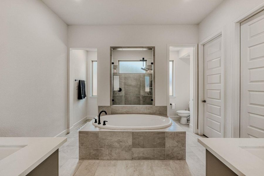 Bathroom with two vanities, a garden tub, tiled shower, and recessed lighting
