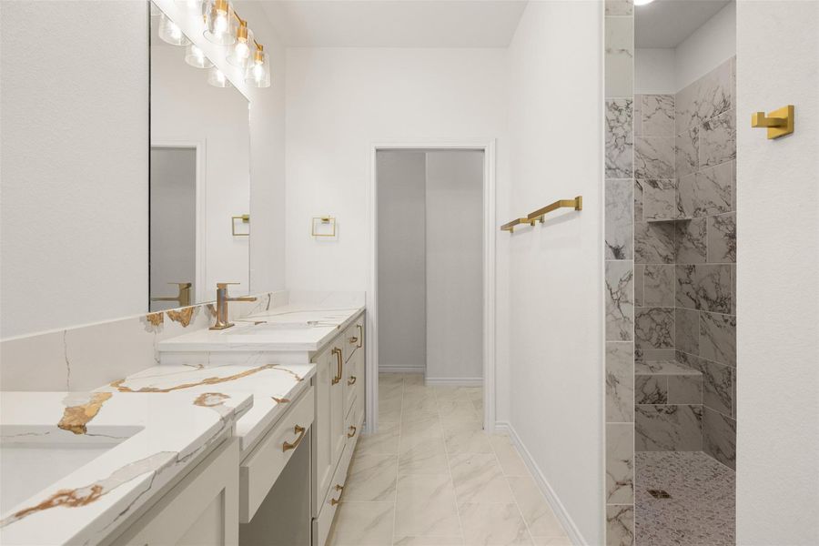 Bathroom featuring a marble finish shower, double vanity, and light marble finish flooring