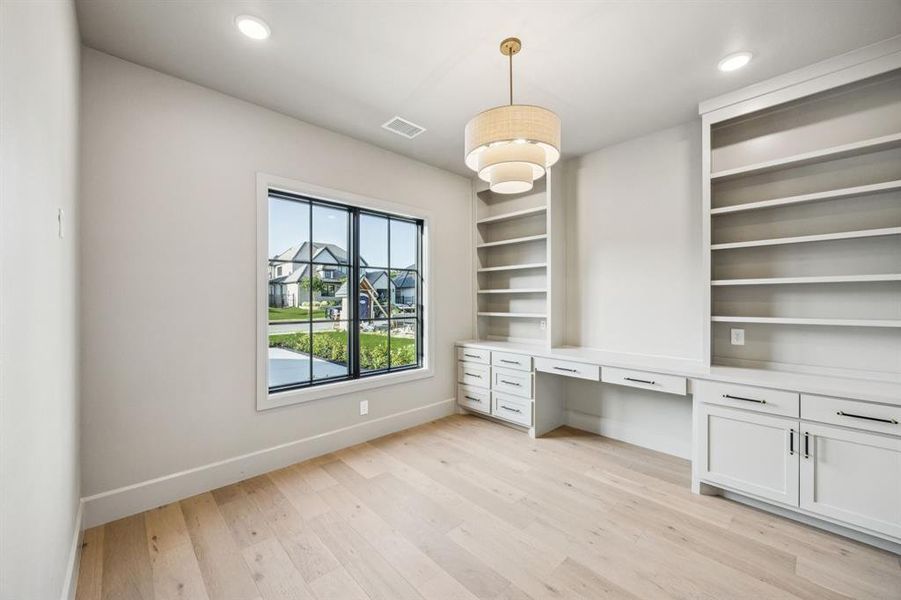Unfurnished office with built in desk, light wood-type flooring, and recessed lighting Unfurnished office with built in desk, light wood-type flooring, and recessed lighting