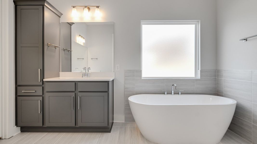 Large tiled bathroom with multiple vanities, glass shower enclosure, and freestanding tub