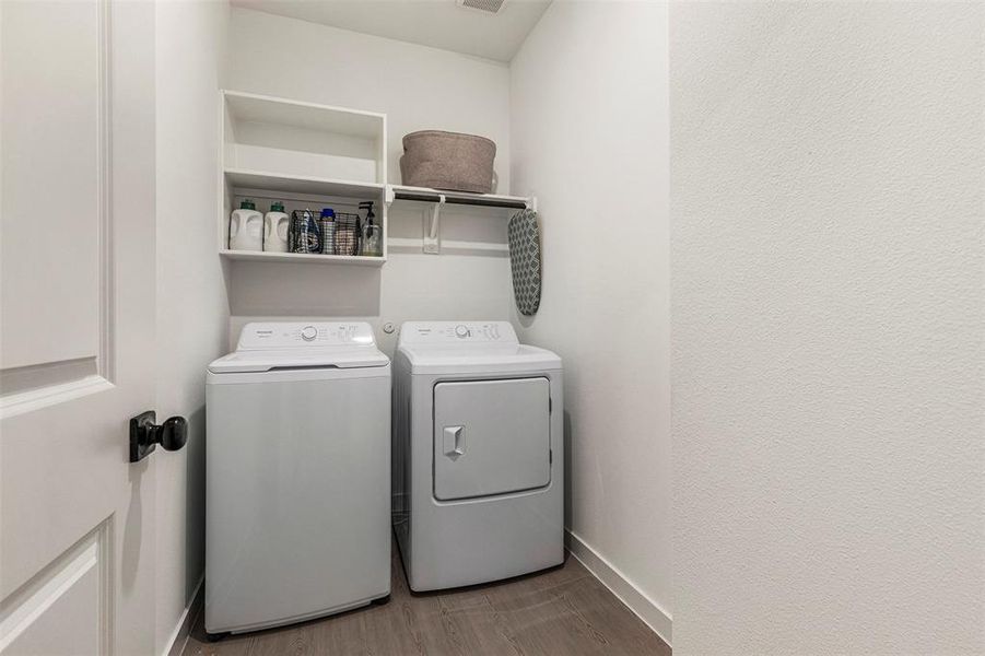 Dedicated laundry area with a washer and dryer, wood-finish flooring, built-in shelving, and white walls Dedicated laundry area with a washer and dryer, wood-finish flooring, built-in shelving, and white walls
