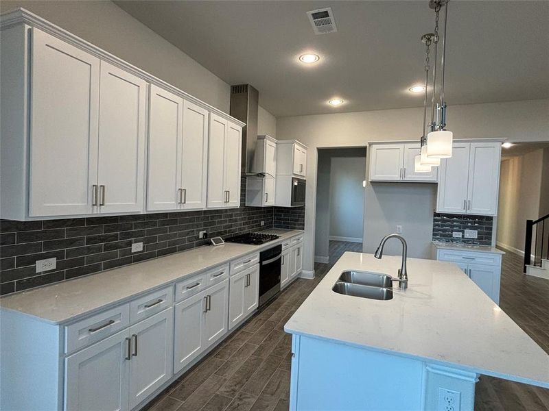 Kitchen featuring white cabinetry, stainless steel appliances, sink, and an island with sink