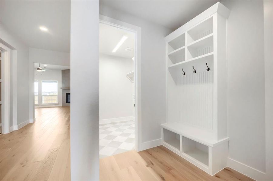 Built-in mudroom station featuring a bench, shelving, beadboard backing, and matte black hooks