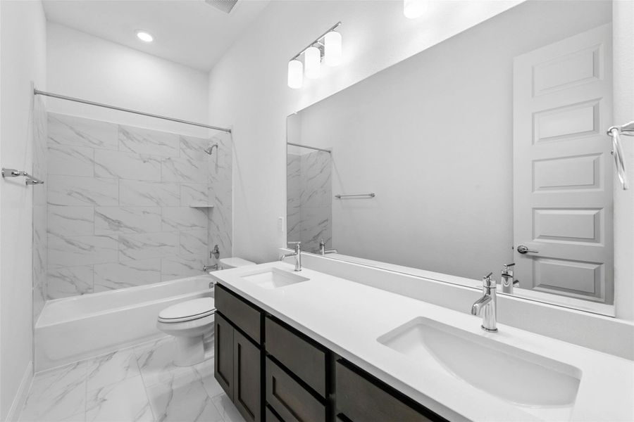 Dual vanities and a tiled shower-tub combo create a functional and stylish primary bathroom.