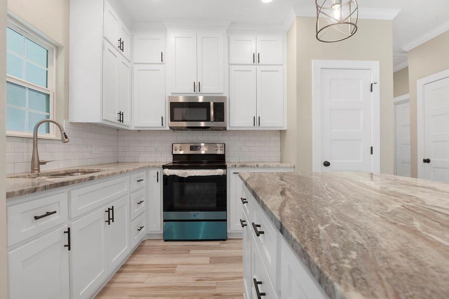 This kitchen features modern white cabinetry, sleek stainless steel appliances, and a stylish marble countertop island. The subway tile backsplash and light wood flooring add a contemporary touch, while the pendant lighting complements the bright, airy space. This kitchen features modern white cabinetry, sleek stainless steel appliances, and a stylish marble countertop island. The subway tile backsplash and light wood flooring add a contemporary touch, while the pendant lighting complements the bright, airy space.
