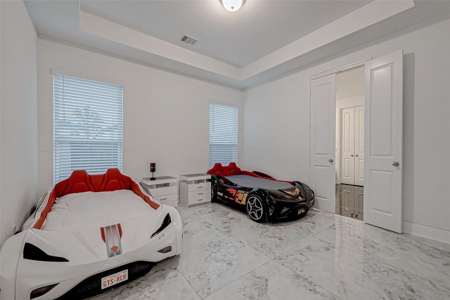 Second Downstairs Primary Suite: Marbled tile floors, tray ceiling, Full ensuite with shower featuring a rainfall system, Jacuzzi tub & double vanities, Walk-in closet with built-in storage