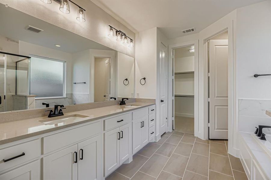 Bathroom featuring double vanity, a garden tub, a stall shower, and light tile patterned floors