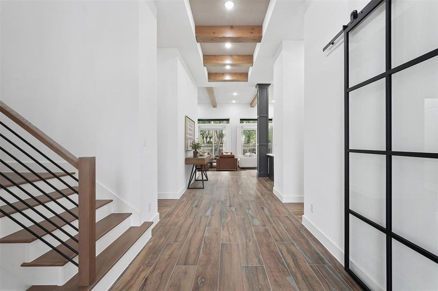 Stroll through the oversized hallway adorned with custom woodwork and upgraded light fixtures seamlessly linking every corner of this remarkable home. To the right, a sleek steel barn door opens to reveal your private study. The impressive hallway, featuring designer flooring and bespoke woodwork, serves as a stylish connective thread throughout the residence.