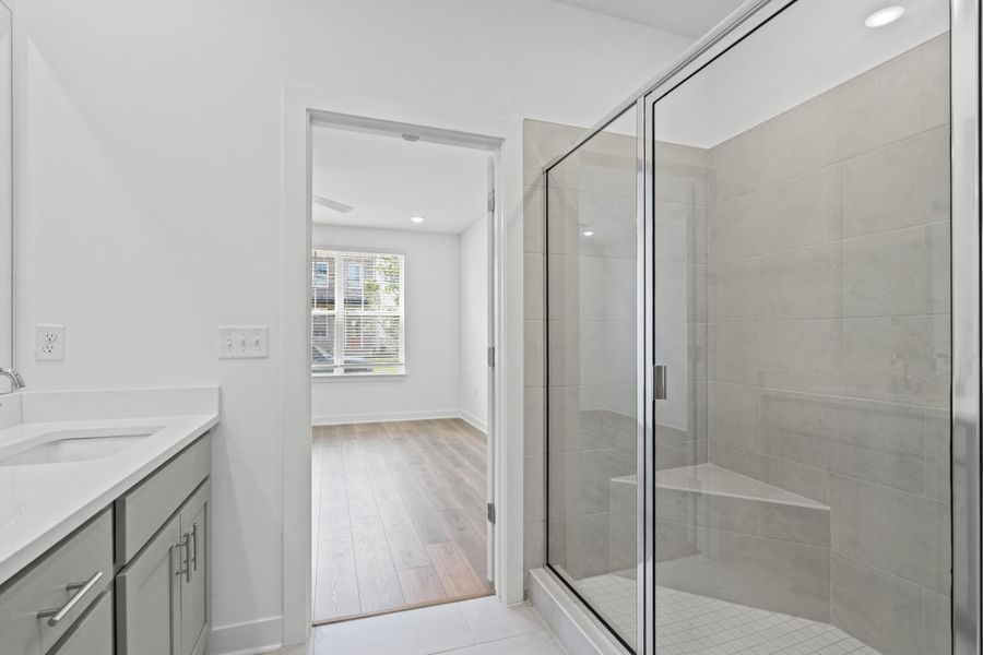 Bathroom featuring a glass-enclosed shower with tile surround and integrated bench