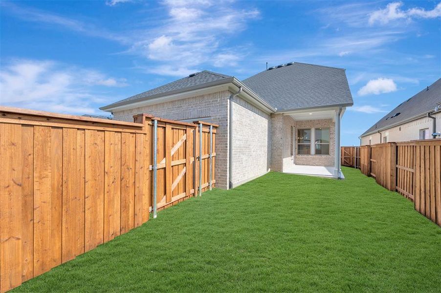 Expansive private yard featuring a manicured lawn, full wood fencing, and a covered concrete patio Expansive private yard featuring a manicured lawn, full wood fencing, and a covered concrete patio