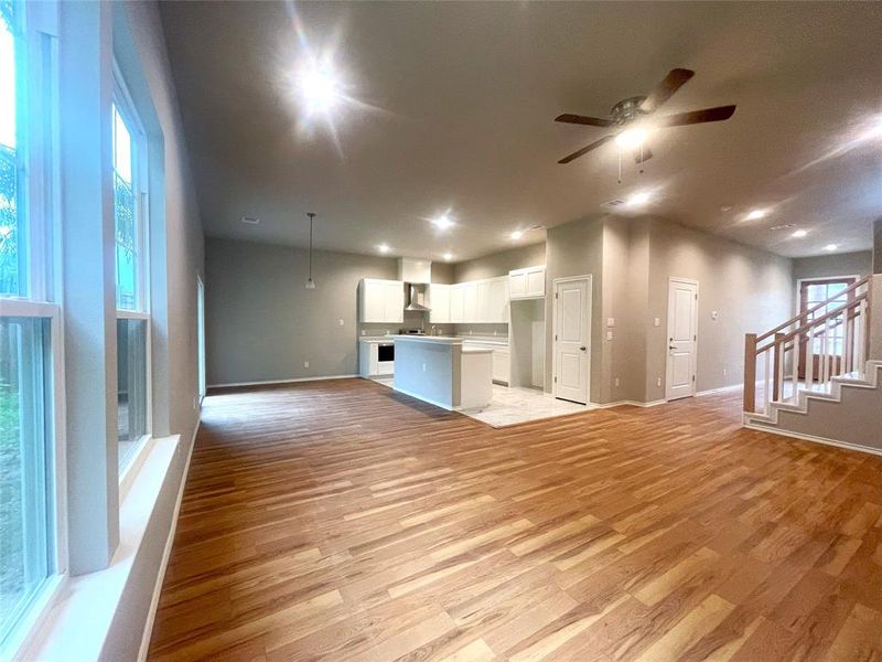 Unfurnished living room with baseboards, ceiling fan, and light wood-style flooring