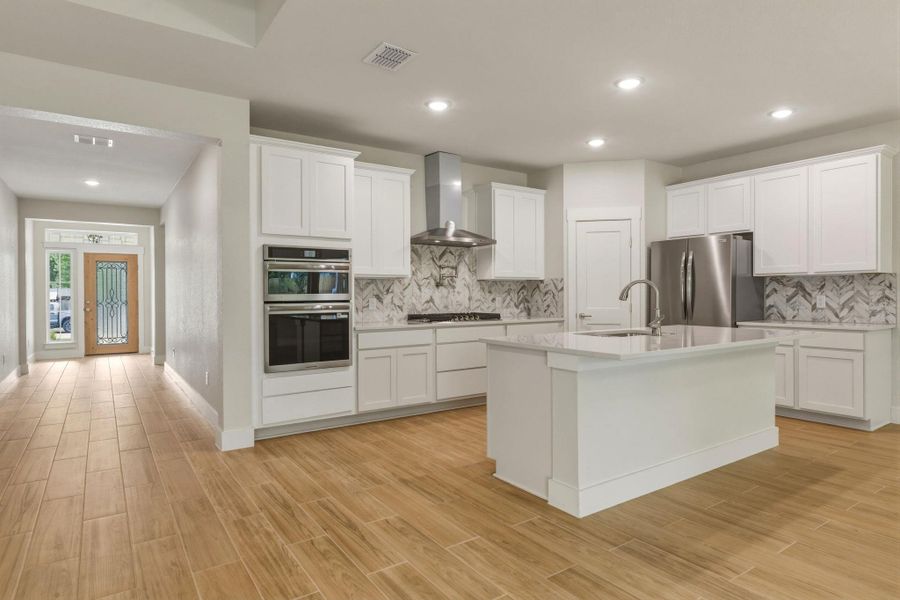 Built-in oven and microwave, gas cooktop, and stainless steel venthood.