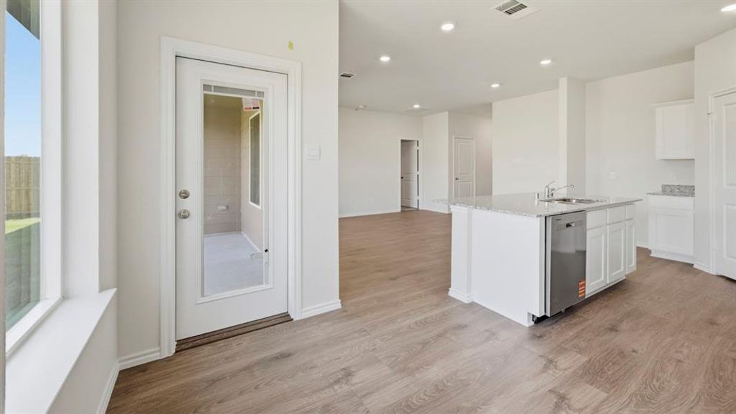 Kitchen with light stone counters, white cabinetry, an island with sink, stainless steel dishwasher, and recessed lighting Kitchen with light stone counters, white cabinetry, an island with sink, stainless steel dishwasher, and recessed lighting