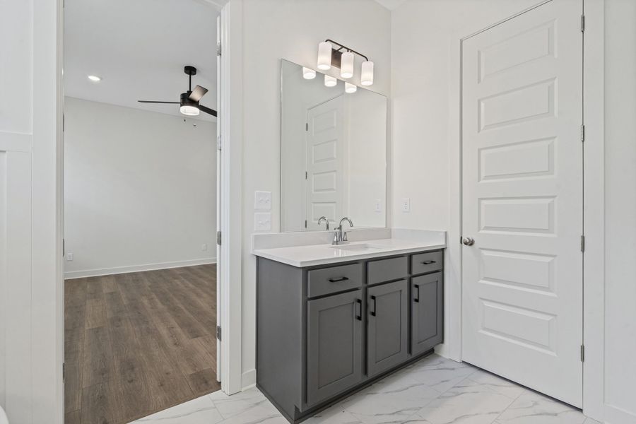 Vanity with gray cabinetry, white countertop, and chrome faucet
