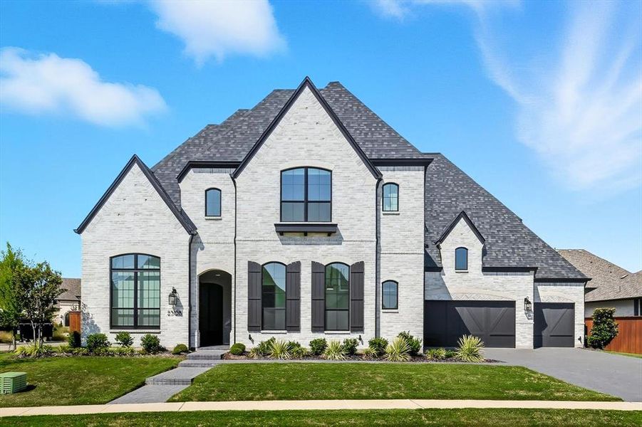 French country style house featuring brick siding, a front lawn, driveway, and impressive 4-car garage French country style house featuring brick siding, a front lawn, driveway, and impressive 4-car garage