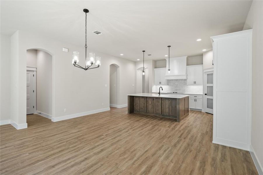 Kitchen featuring a chandelier, white cabinetry, open floor plan, a kitchen island with sink, and recessed lighting