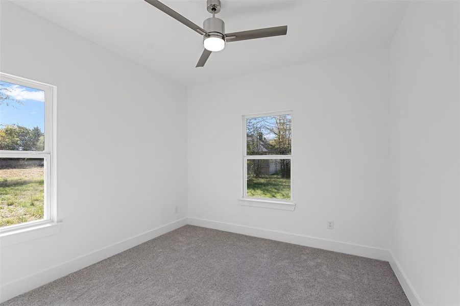 Carpeted spare room with ceiling fan and a healthy amount of sunlight